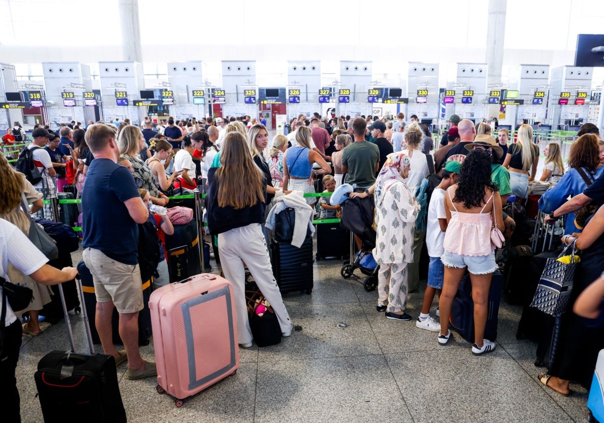 Passengers queue at the check-in desks at Malaga Airport this August peak season.